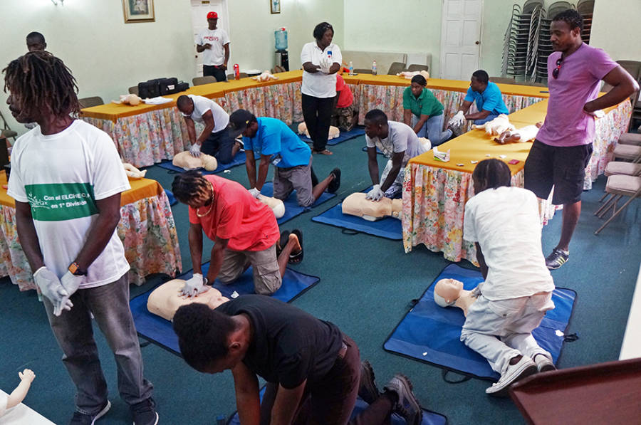 Water-sports operators practice chest compressions for CPR on dummies