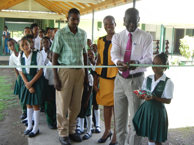 GRENLEC's Branch Manager Wallace Collins cuts ribbon as  his colleague Floyd Best, Principal Barbara Charles and students lo