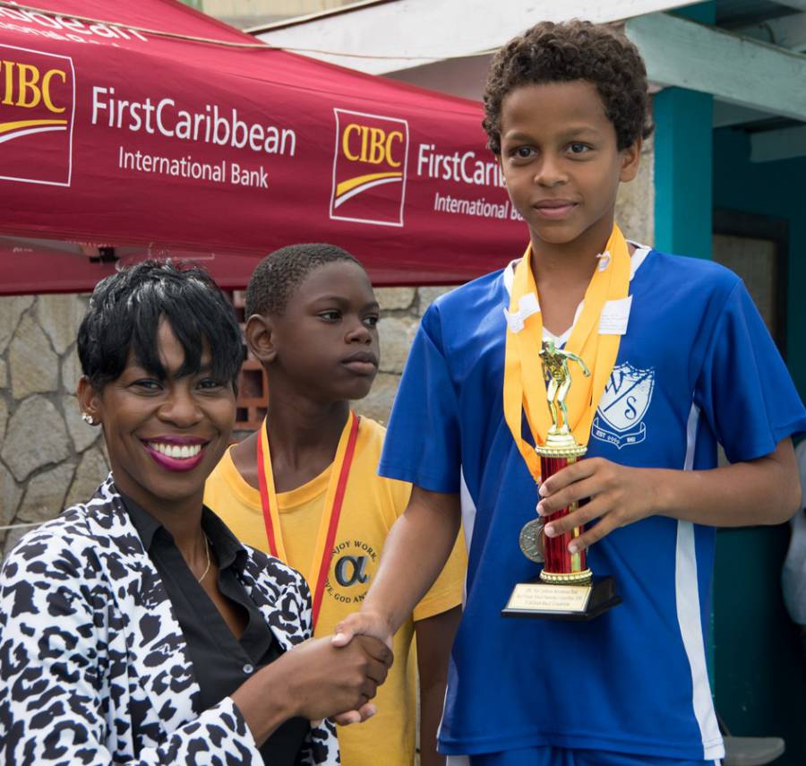 CIBC FirstCaribbean Grand Anse Branch Manager Matonia James Presents Trophy to Zackary Gresham the Top Placing Male Swimmer 