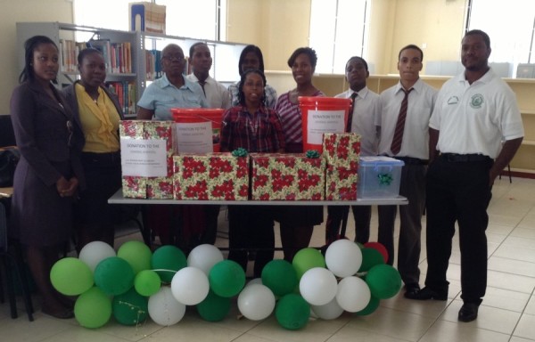 Mrs. Ann David-Antoine of the MOH flanked by teachers and students of the GBSS - on display infront are the items donated to the General Hospital